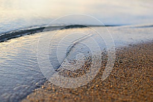 Sea wave and sand seashore. Golden sun light over the sea ocean waves.