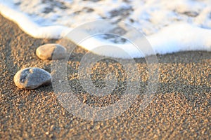 Sea wave on sand and stone at sunrise