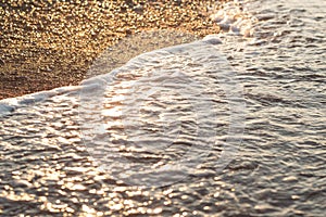 Sea wave on sand and stone at sunrise