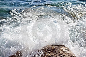 Sea wave splash on rocky beach. Ocean waves breaking on rocks.