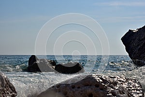 Sea wave splash on rocky beach. Ocean waves breaking on rocks.