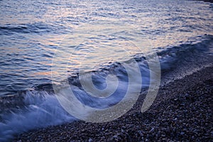 Sea wave at sunset on a background of pebbles