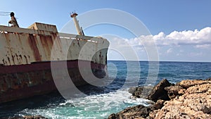 The sea waves beat against the abandoned merchant ship in the Cyprus. View of the crystal clear sea, layered rocks and beautiful n