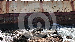 The sea waves beat against the abandoned merchant ship in the Cyprus. View of the crystal clear sea, layered rocks and beautiful n