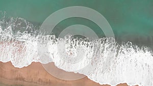 Sea waves and beautiful sand beach. Top view of ocean blue waves break on beach. Bird`s eye view of ocean waves crashing against a