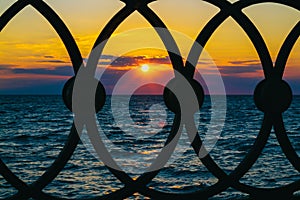 Sea waves and beautiful sky with clouds, view through the fence, sunrsie shot. Copy space.