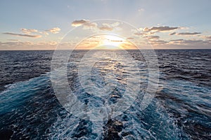 Sea waves behind the ship at sunset