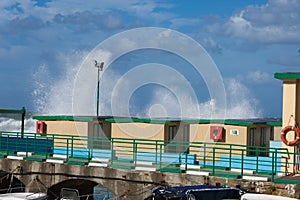 Sea Waves Breaking against Wooden Beach Huts in Windy Day: Stormy Weather