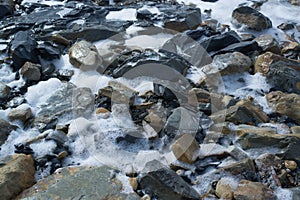 Sea waves are breaking on stones on the shore.