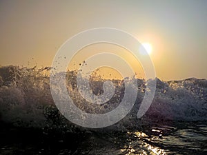 Sea waves crashing against the rocks, at sunset.