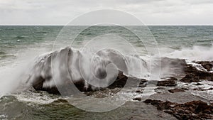 Sea waves crashing hard against a rock in winter