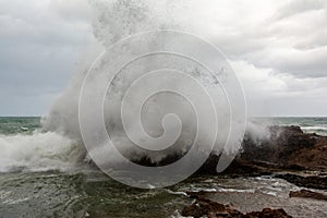 Sea waves crashing hard against a rock in winter