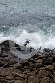 Sea waves crashing on rocks at the edge of the beach of arpoador