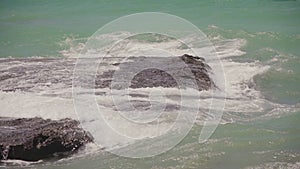 Sea waves crashing on rocks on an empty beach