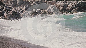 Sea waves crashing on rocks on an empty beach