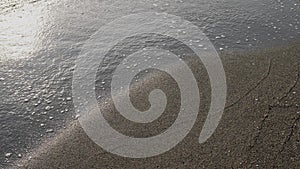 Sea waves and foam on black sand. Beach and relaxation