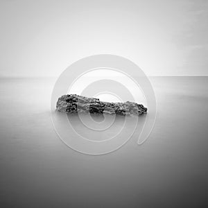 Sea waves lash line impact rock on the beach. Black and white photography.