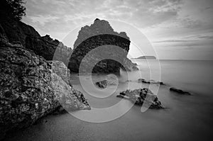 Sea waves lash line impact rock on the beach. Black and white photography.