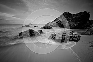 Sea waves lash line impact rock on the beach. Black and white photography.