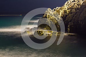 Sea waves lash line impact rock on the beach in night