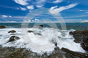 Sea waves lash line impact rock on the beach under blue sky