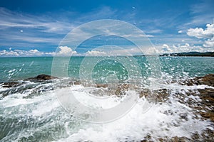 Sea waves lash line impact rock on the beach under blue sky