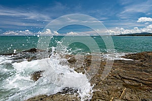 Sea waves lash line impact rock on the beach under blue sky