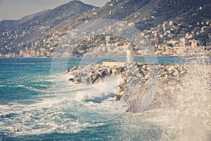 Sea, waves, mountains and lighthouse of Camogli. Italy.