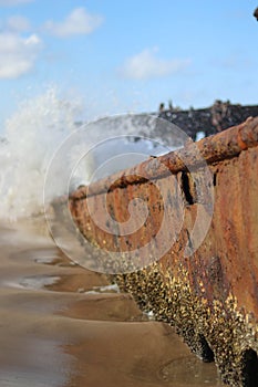 sea waves pound the wreckage of a rusted wrecked ship photo