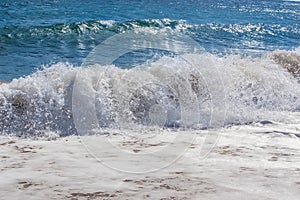 Sea waves roll on to shore with foam and sea spray.