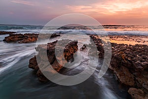 Sea waves splashing over the rocks at sunset, Mollymook, NSW South Coast, Australia