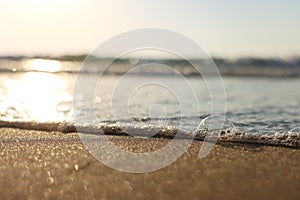 Sea waves and warm sunset light, calm and relaxing sandy beach