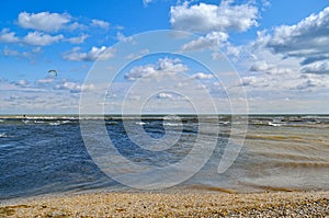 Sea waves wash the beach against a blue sky. Landscape on a wild beach. The sea in the summer