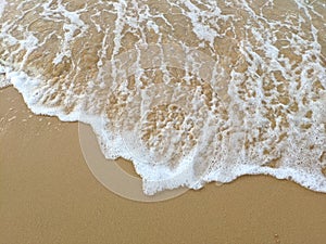 Sea waves with white foams on yellow sand