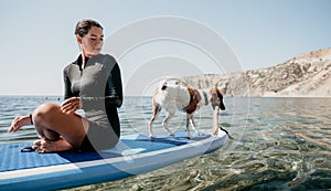 Sea woman sup. Silhouette of happy positive young woman with her dog, surfing on SUP board through calm water surface