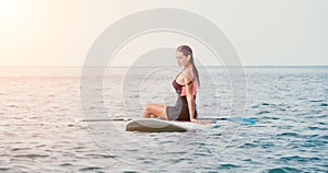 Sea woman sup. Silhouette of happy young woman in pink bikini, surfing on SUP board, confident paddling through water