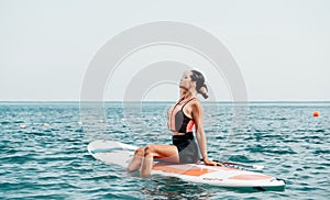 Sea woman sup. Silhouette of happy young woman in pink bikini, surfing on SUP board, confident paddling through water