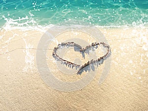 Sea â€‹â€‹beach on the sand element drawn hearts ocean wave and water splash on tropical beach summer vacation