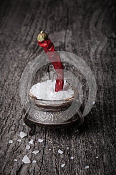 Sea â€‹â€‹salt in a large antique salt shaker and hot red pepper