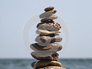 Sea â€‹â€‹stones to each other in the form of a tower against the background of the sea and sky