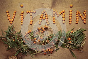 Seabuckthorn berries, leaves and branches on a wooden background.