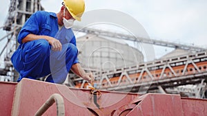 Seafarer checks protective lead seal to safely lock cargo holds with wheat on bulker ship at sea grain terminal in