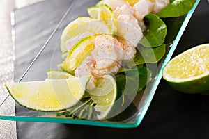 Seafood ceviche from hake on a glass plate with lime and greens