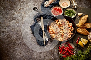 Grilled shrimps in cast iron grilling pan with fresh lemon, parsley, chili, garlic white wine sauce