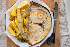 Seafood dish, grilled steak from swordfish or spada served with french fried potatoes and green olives photo