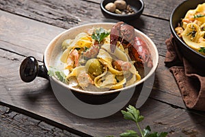 Seafood fettuccine pasta with crayfishes, octopus shrimps, on stone pan. Gourmet dish