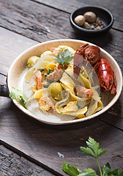 Seafood fettuccine pasta with crayfishes, octopus shrimps, on stone pan. Gourmet dish