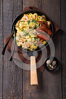 Seafood fettuccine pasta with crayfishes, octopus shrims, on stone pan. Gourmet dish