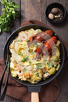 Seafood fettuccine pasta with crayfishes, octopus shrims, on stone pan. Gourmet dish