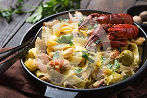 Seafood fettuccine pasta with crayfishes, octopus shrims, on stone pan. Gourmet dish